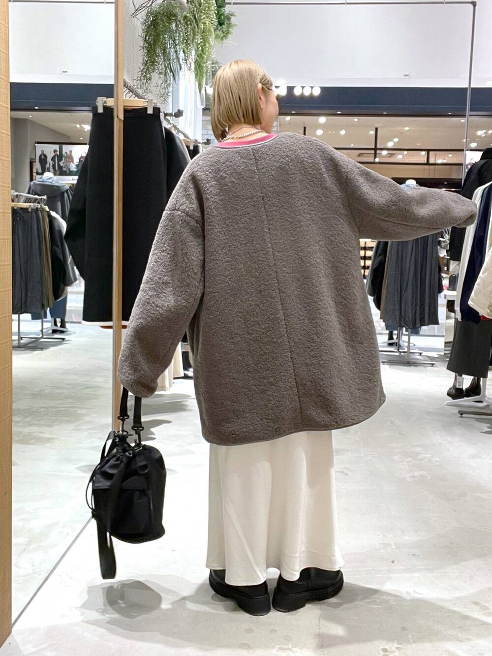 ブラック系のショルダーバッグ、ホワイト系のスカート、ブラウン系のその他アウターを着用したレディースの秋コーディネートの2枚目の写真