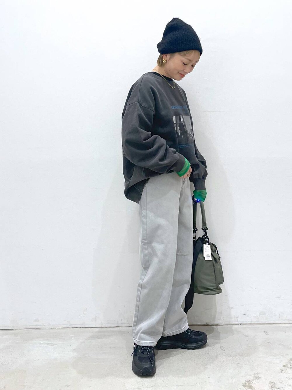 グリーン系のショルダーバッグ、ブラック系のTシャツ/カットソー、グレー系のデニムパンツを着用したレディースの冬コーディネートの2枚目の写真
