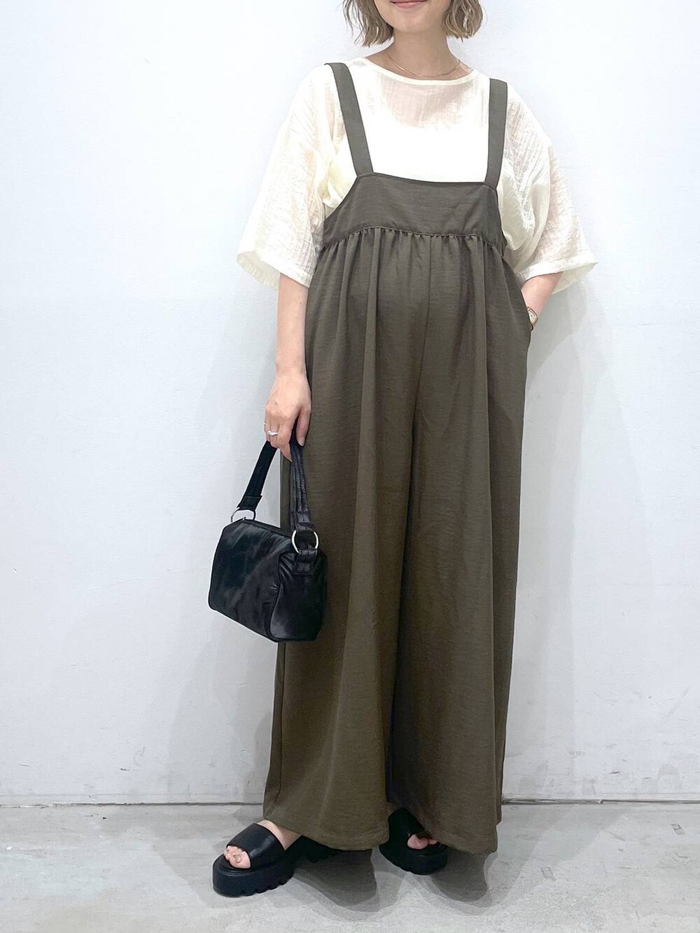 グリーン系のサロペット/オーバーオール、ブラック系のハンドバッグ、ブラック系のサンダルを着用したレディースの夏コーディネートの3枚目の写真