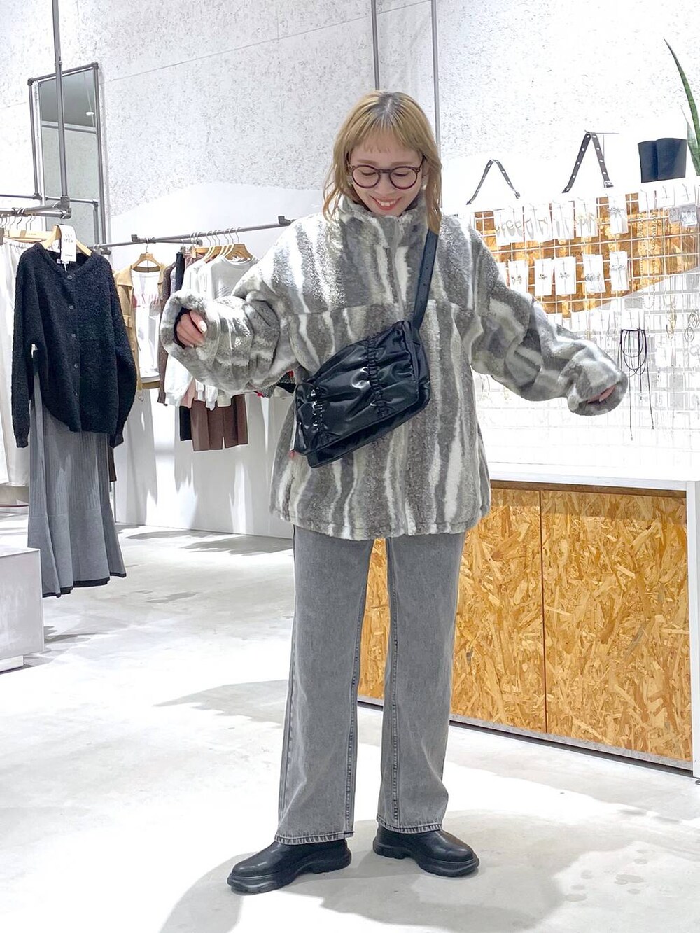 ブラック系のショルダーバッグ、ホワイト系のブルゾン、グレー系のデニムパンツを着用したレディースの秋コーディネートの4枚目の写真