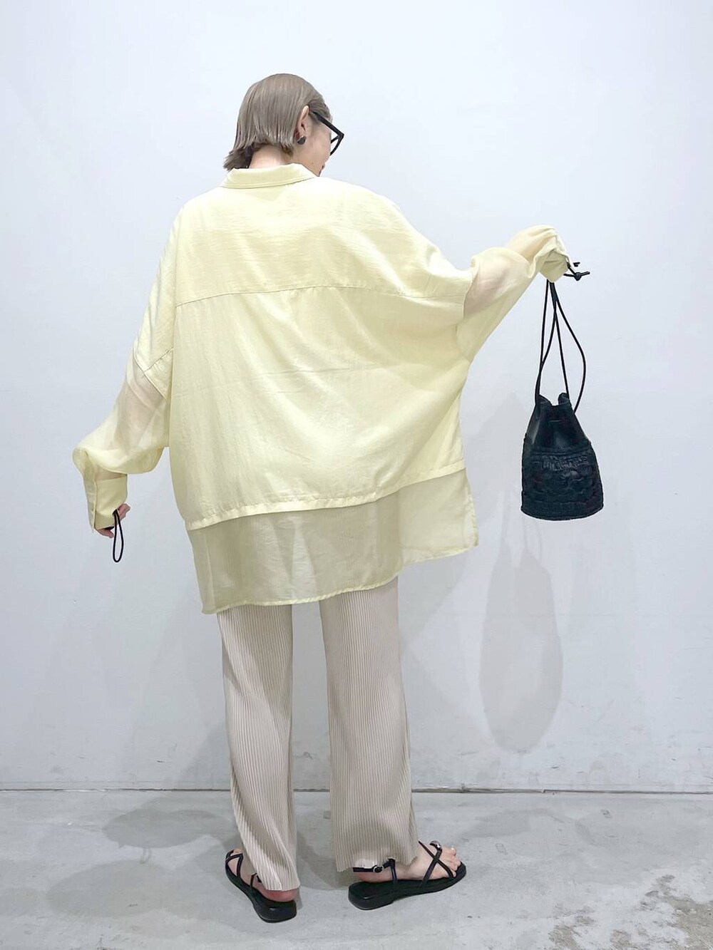 ブラック系のショルダーバッグ、イエロー系のシャツ/ブラウス、ベージュ系のその他パンツを着用したレディースの夏コーディネートの3枚目の写真