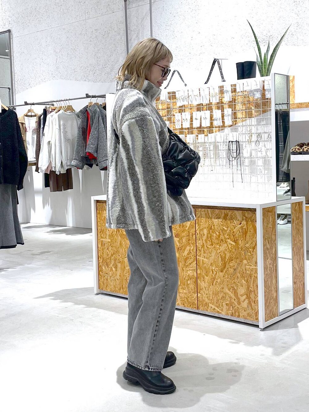 ブラック系のショルダーバッグ、ホワイト系のブルゾン、グレー系のデニムパンツを着用したレディースの秋コーディネートの2枚目の写真