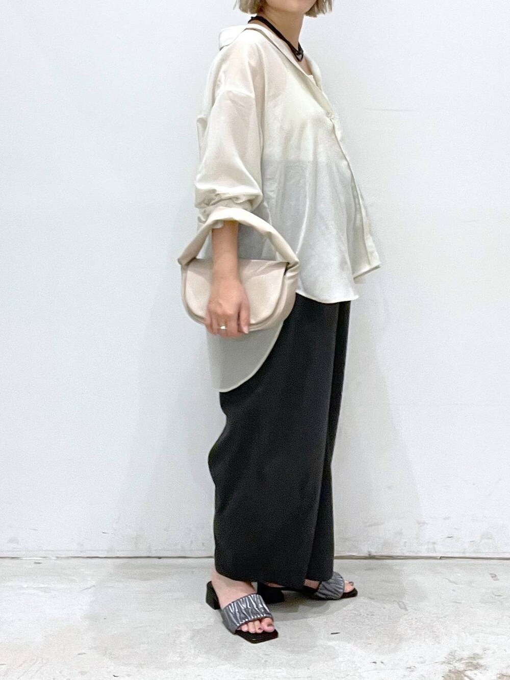 ベージュ系のハンドバッグ、シルバー系のサンダル、ホワイト系のシャツ/ブラウスを着用したレディースの夏コーディネートの2枚目の写真