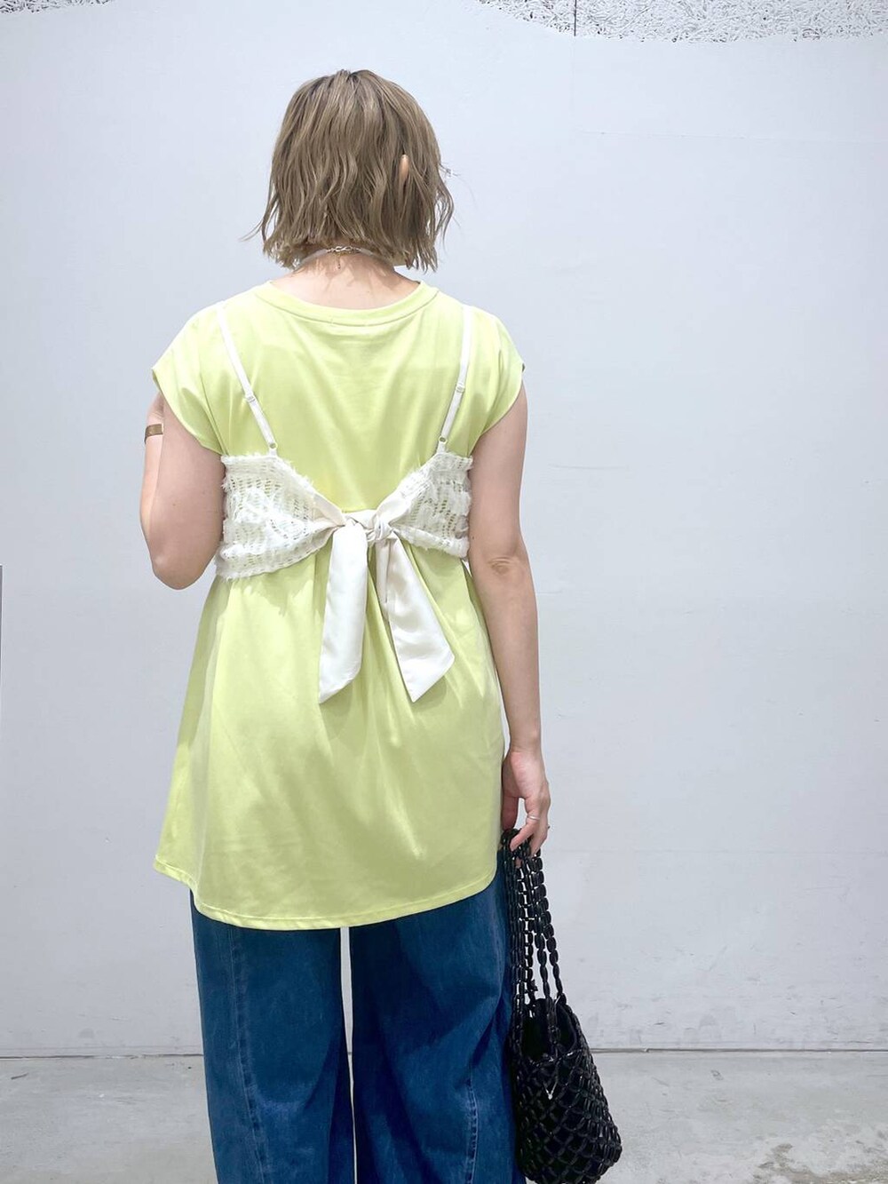 ブルー系のデニムパンツ、グリーン系のTシャツ/カットソー、ブラック系のサンダルを着用したレディースの夏コーディネートの3枚目の写真