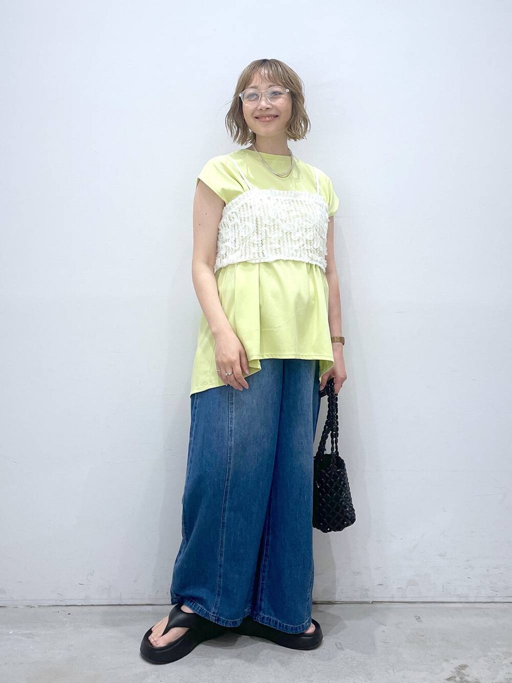 ブルー系のデニムパンツ、グリーン系のTシャツ/カットソー、ブラック系のサンダルを着用したレディースの夏コーディネートの4枚目の写真