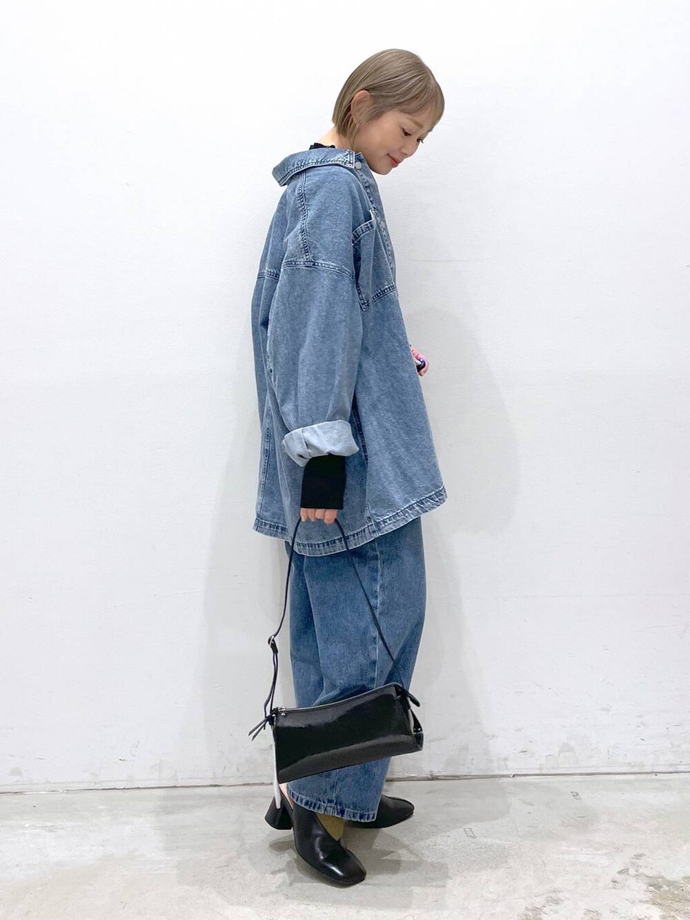 ブラック系のニット/セーター、ブルー系のデニムパンツ、ブラック系のパンプスを着用したレディースの冬コーディネートの2枚目の写真