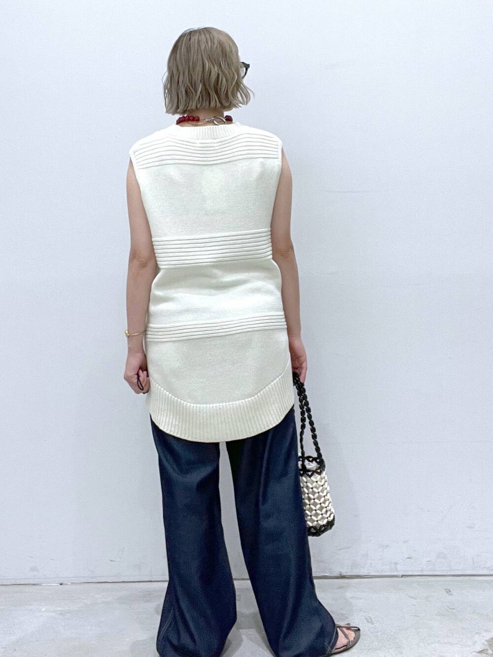 ブルー系のデニムパンツ、その他のサンダル、ホワイト系のハンドバッグを着用したレディースの夏コーディネートの3枚目の写真