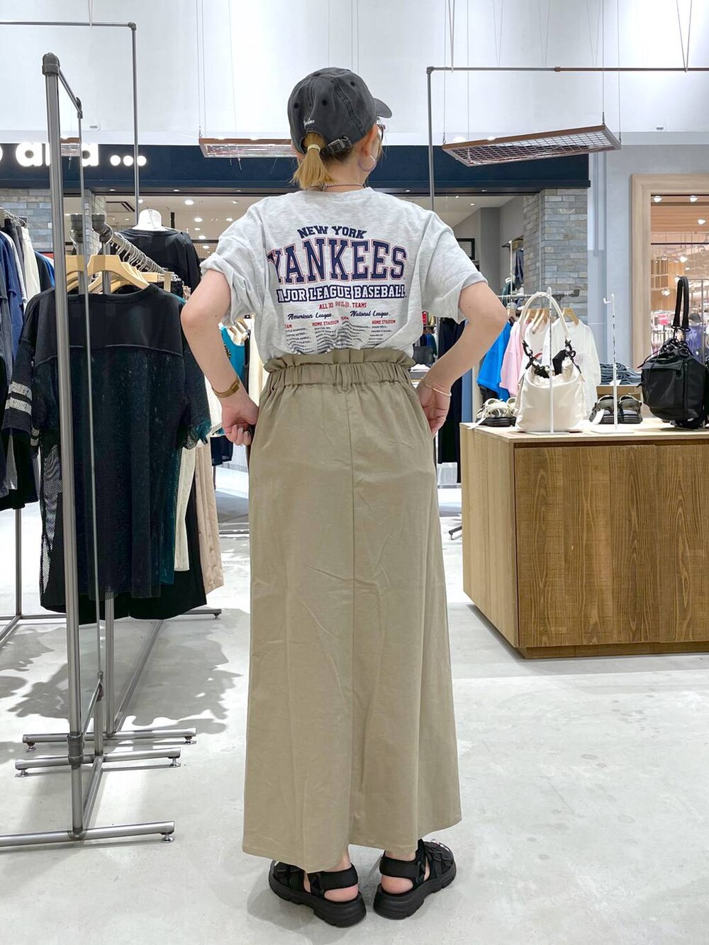 ブラック系のサンダル、ベージュ系のTシャツ/カットソー、グリーン系のスカートを着用したレディースの夏コーディネートの3枚目の写真