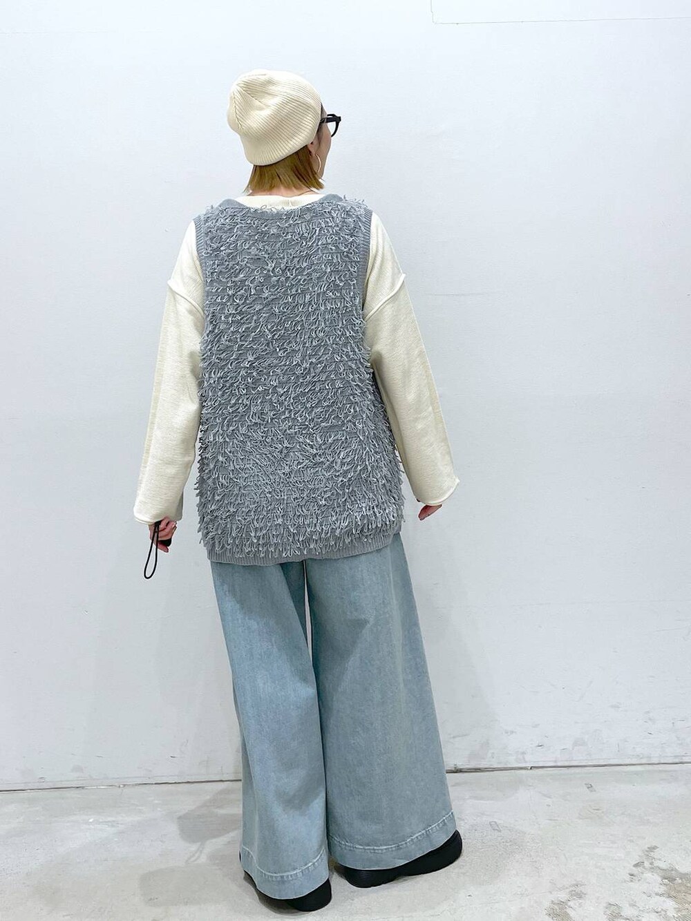ブルー系のデニムパンツ、ブラック系のサンダル、グレー系のベストを着用したレディースの春コーディネートの3枚目の写真