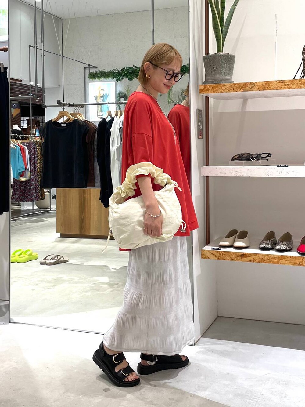 ホワイト系のショルダーバッグ、ブラック系のサンダル、レッド系のTシャツ/カットソーを着用したレディースの夏コーディネートの2枚目の写真