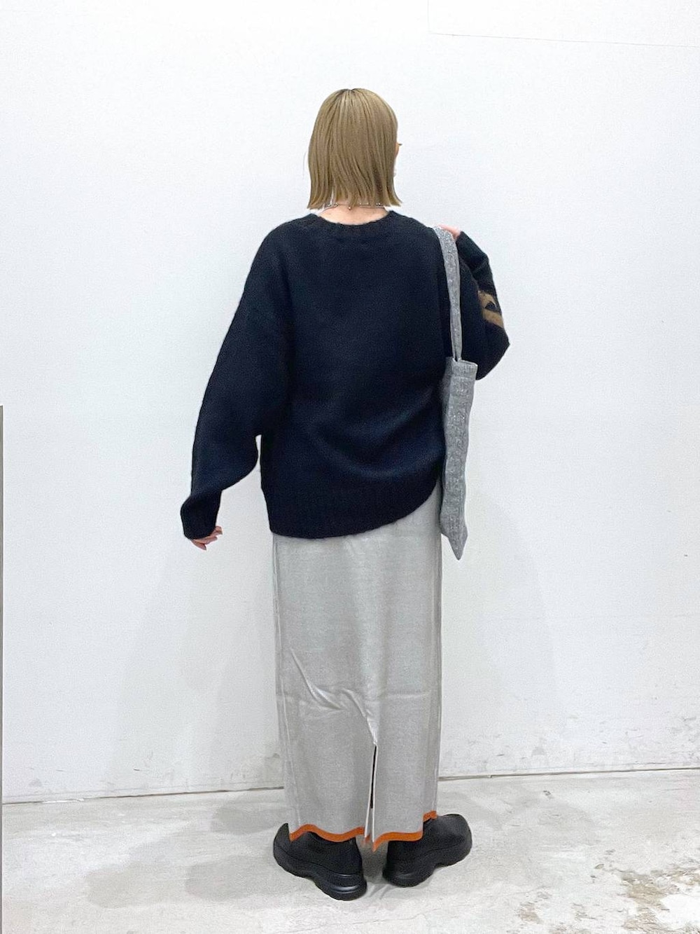 シルバー系のトートバッグ、グレー系のスカート、ブラック系のブーツを着用したレディースの冬コーディネートの3枚目の写真
