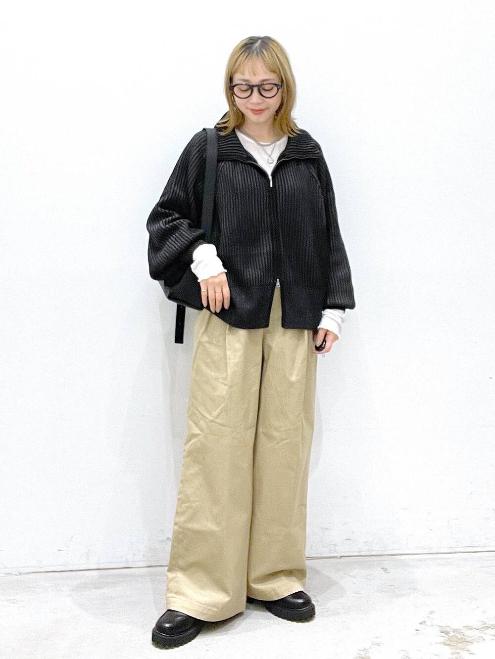 ベージュ系のチノパンツ、ブラック系のブーツ、ブラック系のカーディガン/ボレロを着用したレディースの秋コーディネートの5枚目の写真