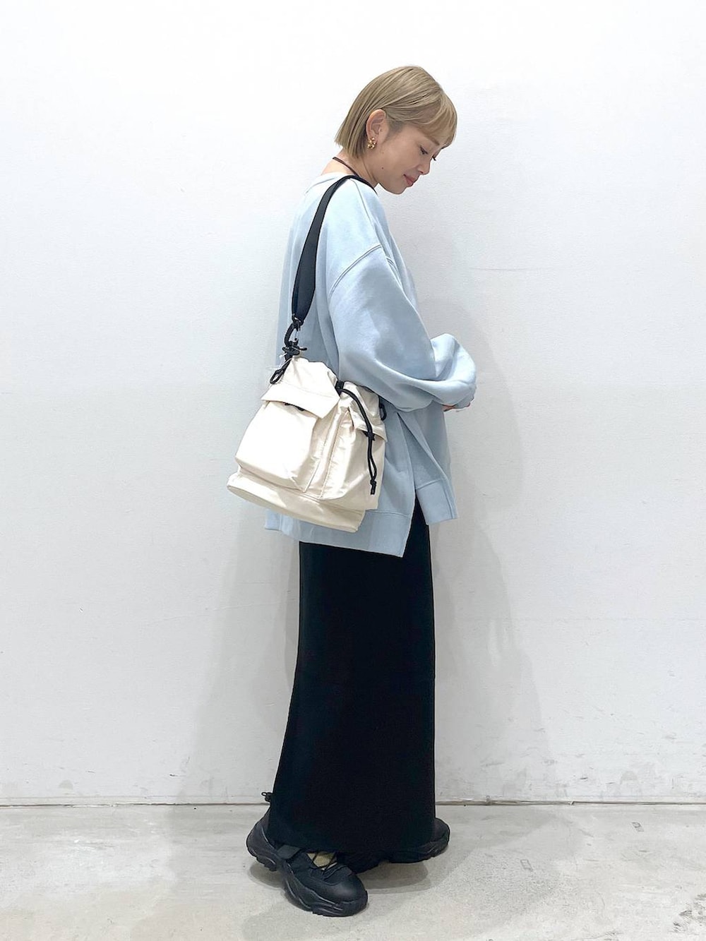 ホワイト系のショルダーバッグ、ブラック系のスカート、ブラック系のスニーカーを着用したレディースの冬コーディネートの2枚目の写真