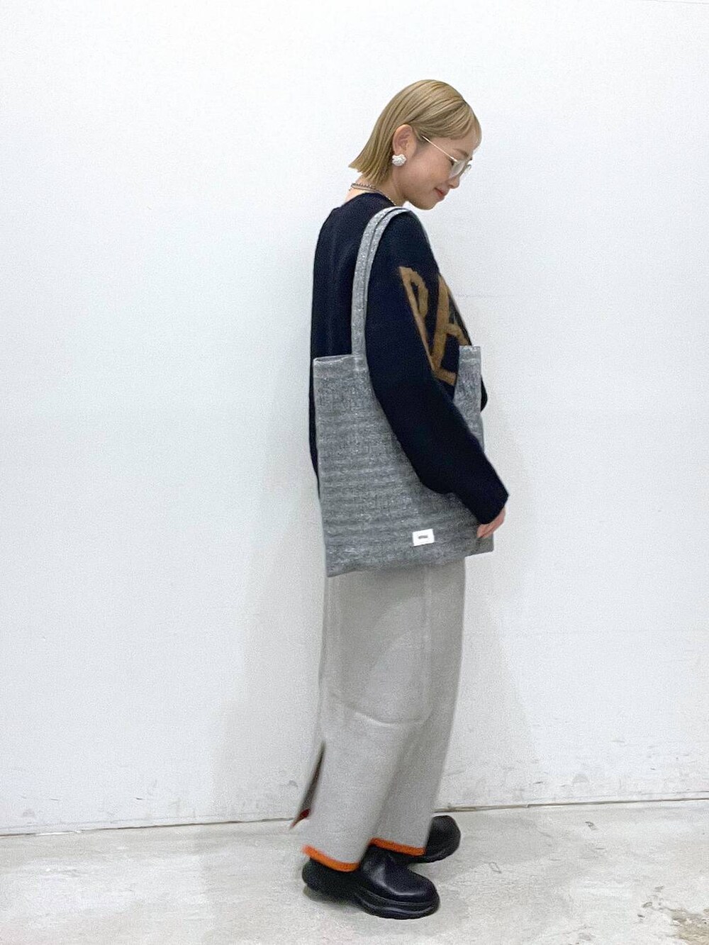 シルバー系のトートバッグ、グレー系のスカート、ブラック系のブーツを着用したレディースの冬コーディネートの2枚目の写真