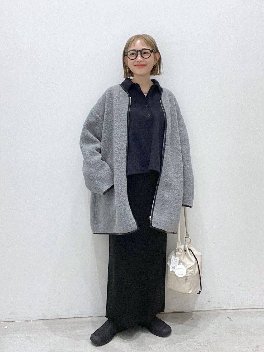 ブラック系のスカート、グレー系のその他アウター、ホワイト系のショルダーバッグを着用したレディースの秋コーディネートの4枚目の写真