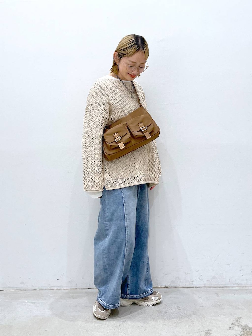 ホワイト系のニット/セーター、ブルー系のデニムパンツ、ホワイト系のTシャツ/カットソーを着用したレディースの春コーディネートの2枚目の写真