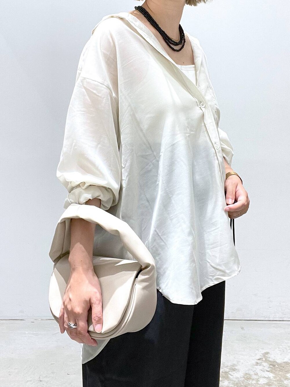 ベージュ系のハンドバッグ、シルバー系のサンダル、ホワイト系のシャツ/ブラウスを着用したレディースの夏コーディネートの4枚目の写真