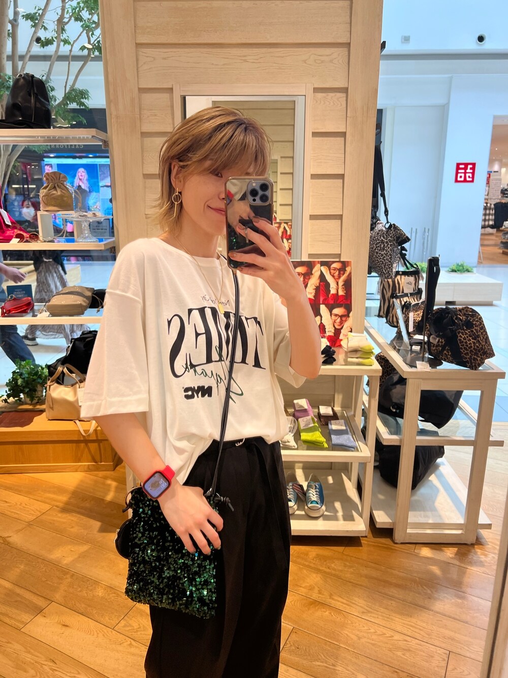 ブラック系のスラックス、グリーン系のショルダーバッグ、ホワイト系のTシャツ/カットソーを着用したレディースの夏コーディネートの2枚目の写真