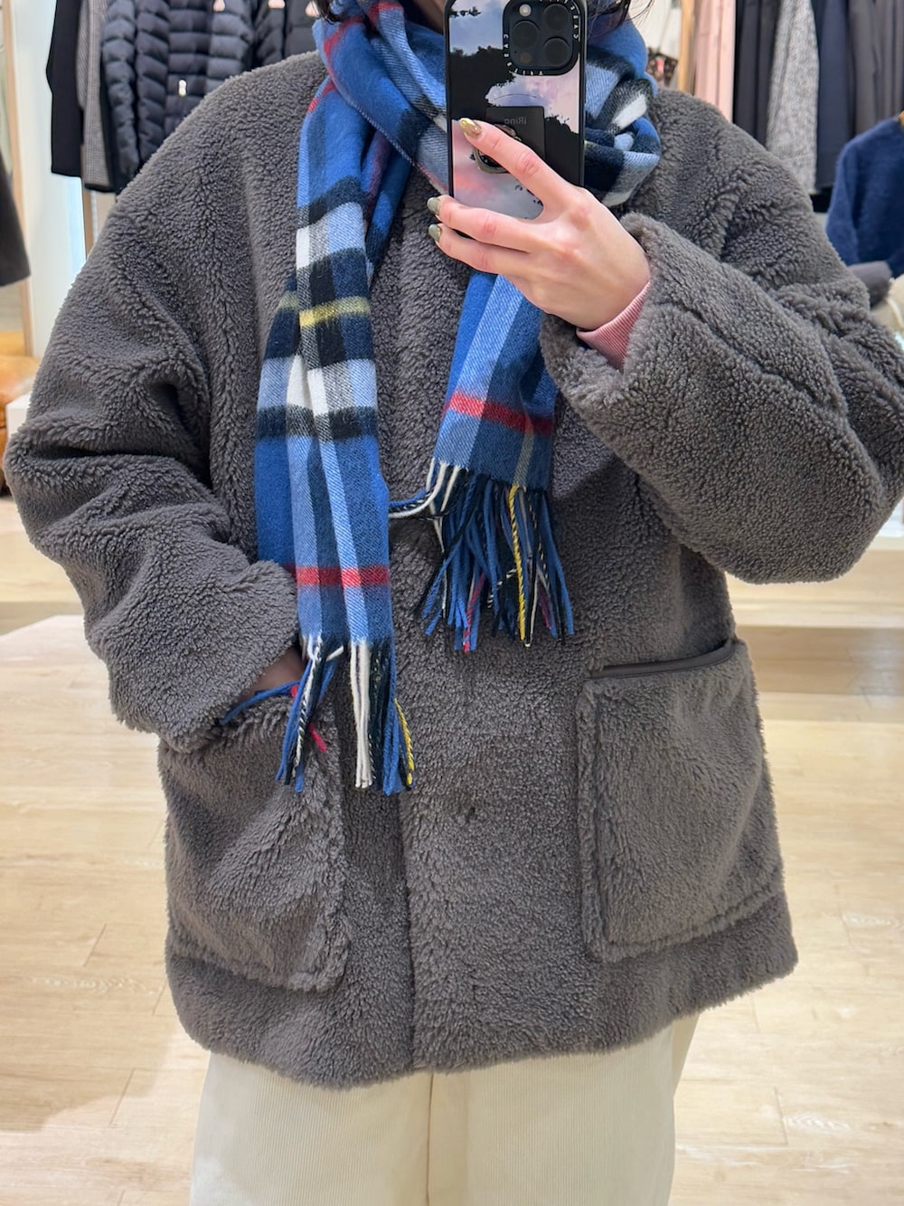 ブラウン系のノーカラーコート、ホワイト系のその他パンツ、ブルー系のストール/ショールを着用したレディースの冬コーディネートの3枚目の写真