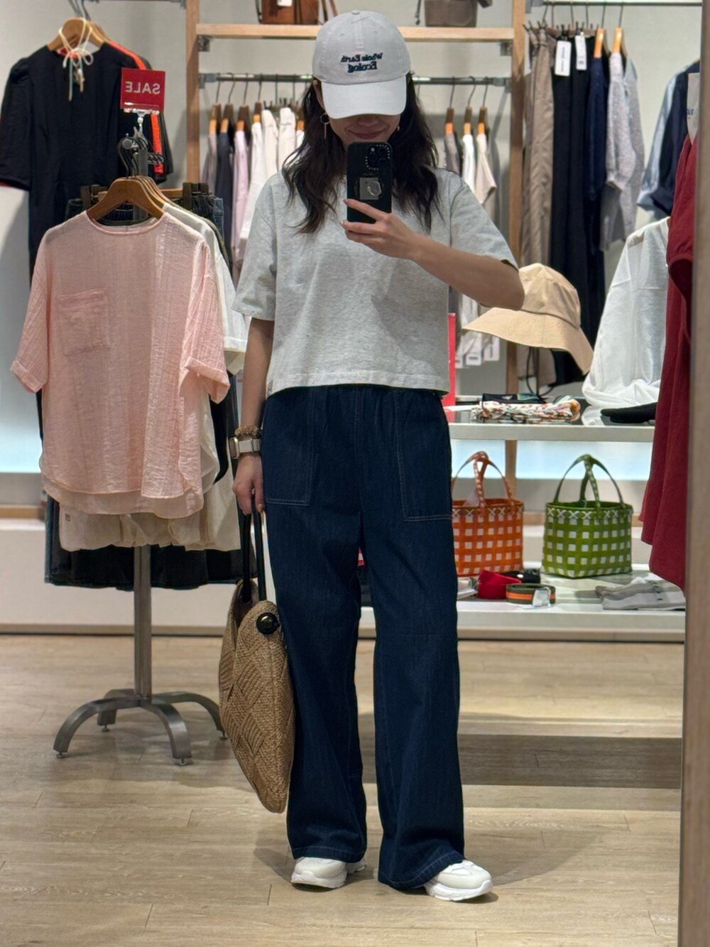 グレー系のTシャツ/カットソー、ブルー系のデニムパンツ、ベージュ系のかごバッグを着用したレディースの夏コーディネートの2枚目の写真