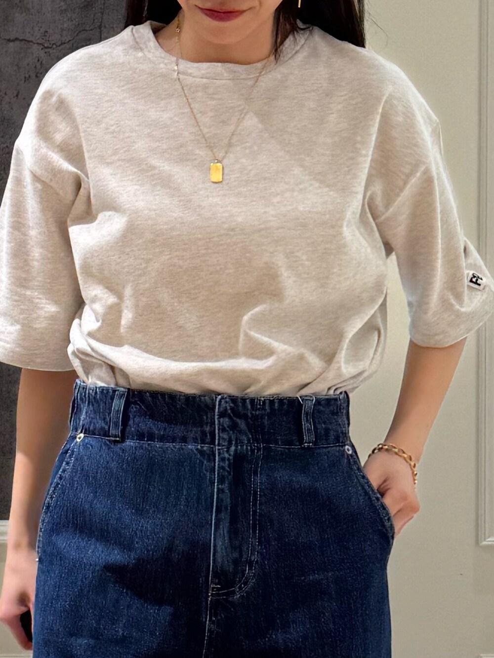 ベージュ系のTシャツ/カットソー、ブルー系のデニムパンツ、ブラック系のサンダルを着用したレディースの春コーディネートの3枚目の写真