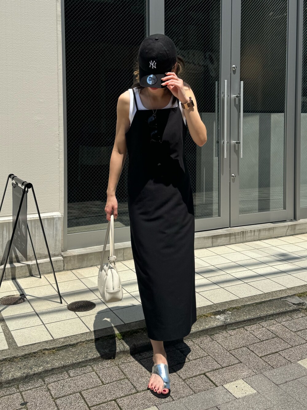 ブラック系のワンピース、ホワイト系のボストンバッグ、シルバー系のサンダルを着用したレディースの夏コーディネートの2枚目の写真