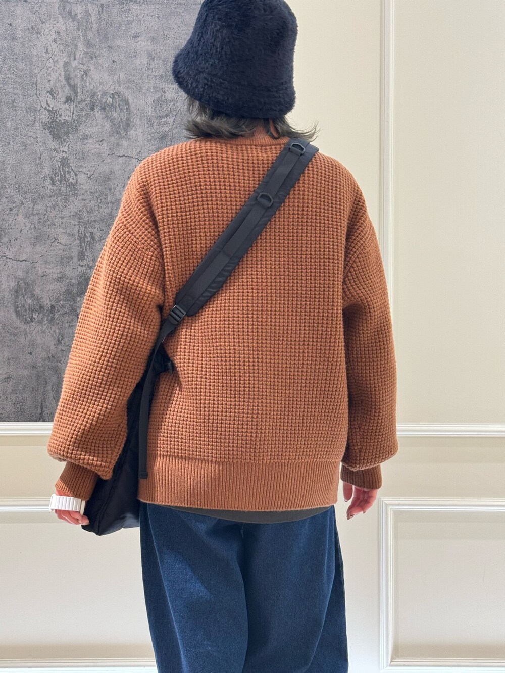 イエロー系のニット/セーター、ブルー系のデニムパンツ、ブラック系のショルダーバッグを着用したレディースの冬コーディネートの3枚目の写真