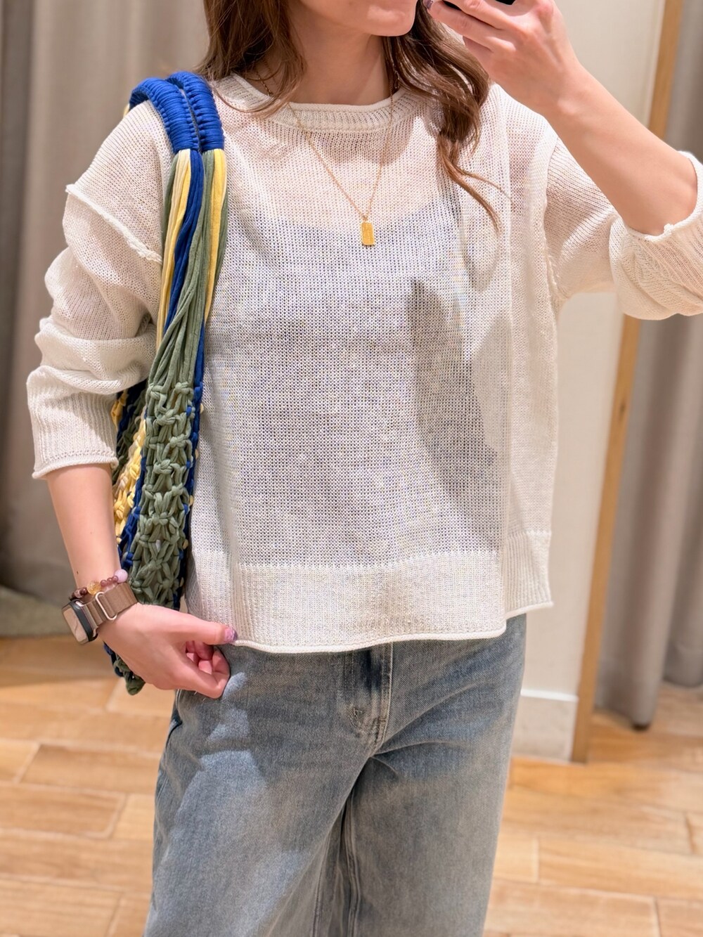 ホワイト系のニット/セーター、ブルー系のデニムパンツ、ブラック系のトートバッグを着用したレディースの春コーディネートの2枚目の写真