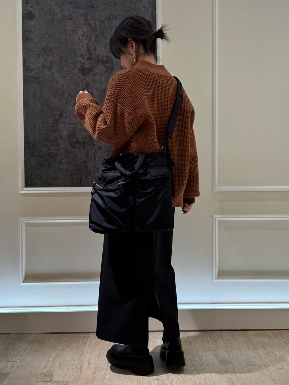 イエロー系のニット/セーター、ホワイト系のスカート、ブラック系のショルダーバッグを着用したレディースの冬コーディネートの2枚目の写真