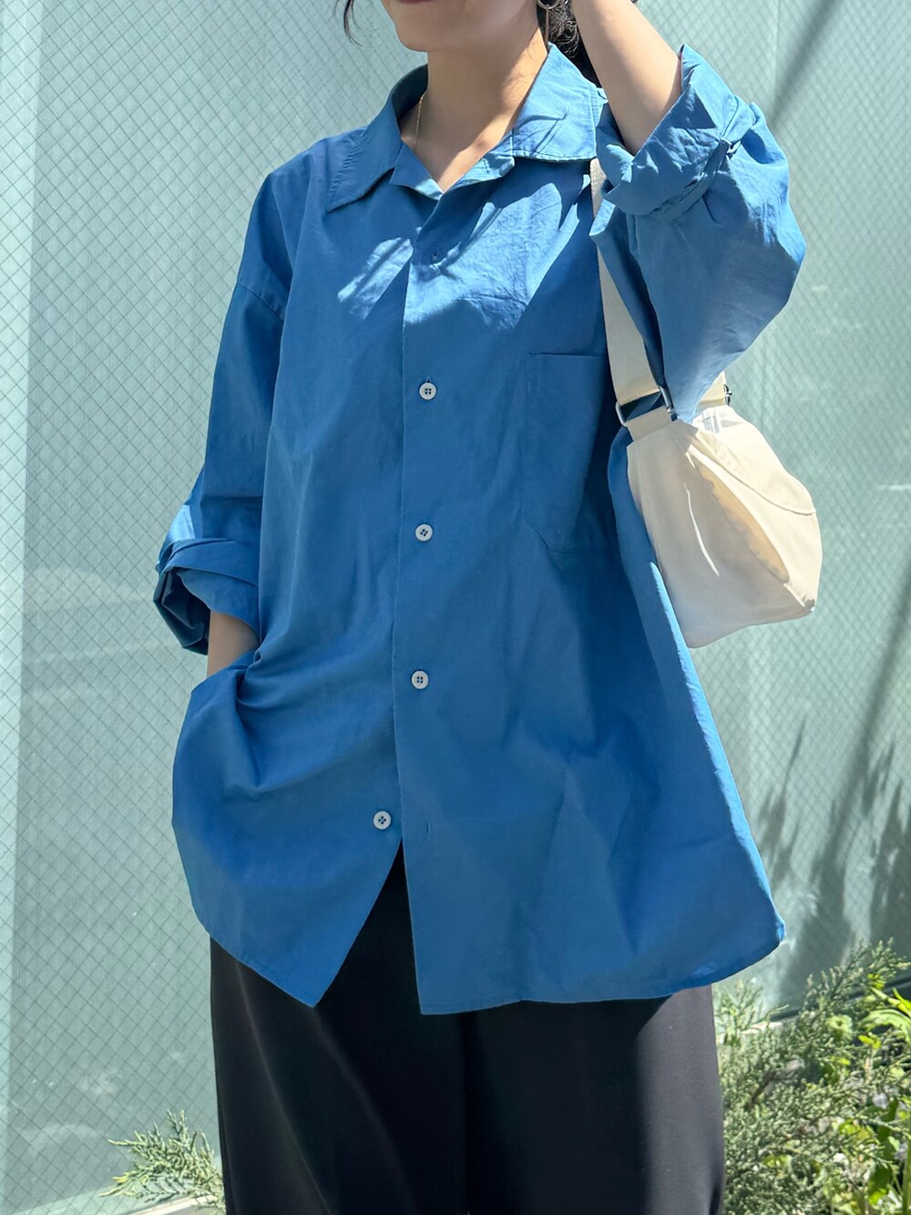 ブルー系のシャツ/ブラウス、グレー系のスラックス、ホワイト系のショルダーバッグを着用したレディースの春コーディネートの3枚目の写真