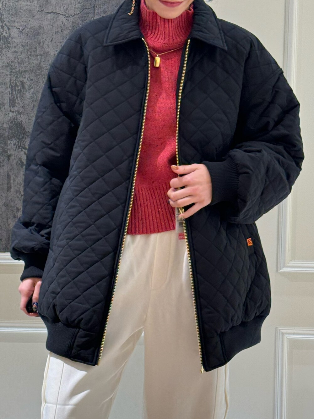 ブラック系のブルゾン、ホワイト系のカーゴパンツ、ピンク系のニット/セーターを着用したレディースの冬コーディネートの2枚目の写真