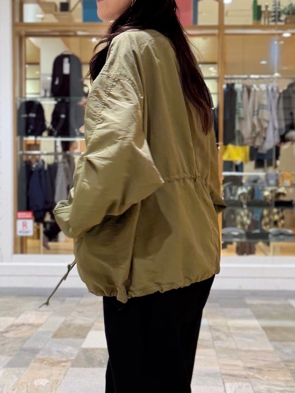 グリーン系のブルゾン、ブラック系のその他パンツ、ブラック系のキャップを着用したレディースの秋コーディネートの2枚目の写真