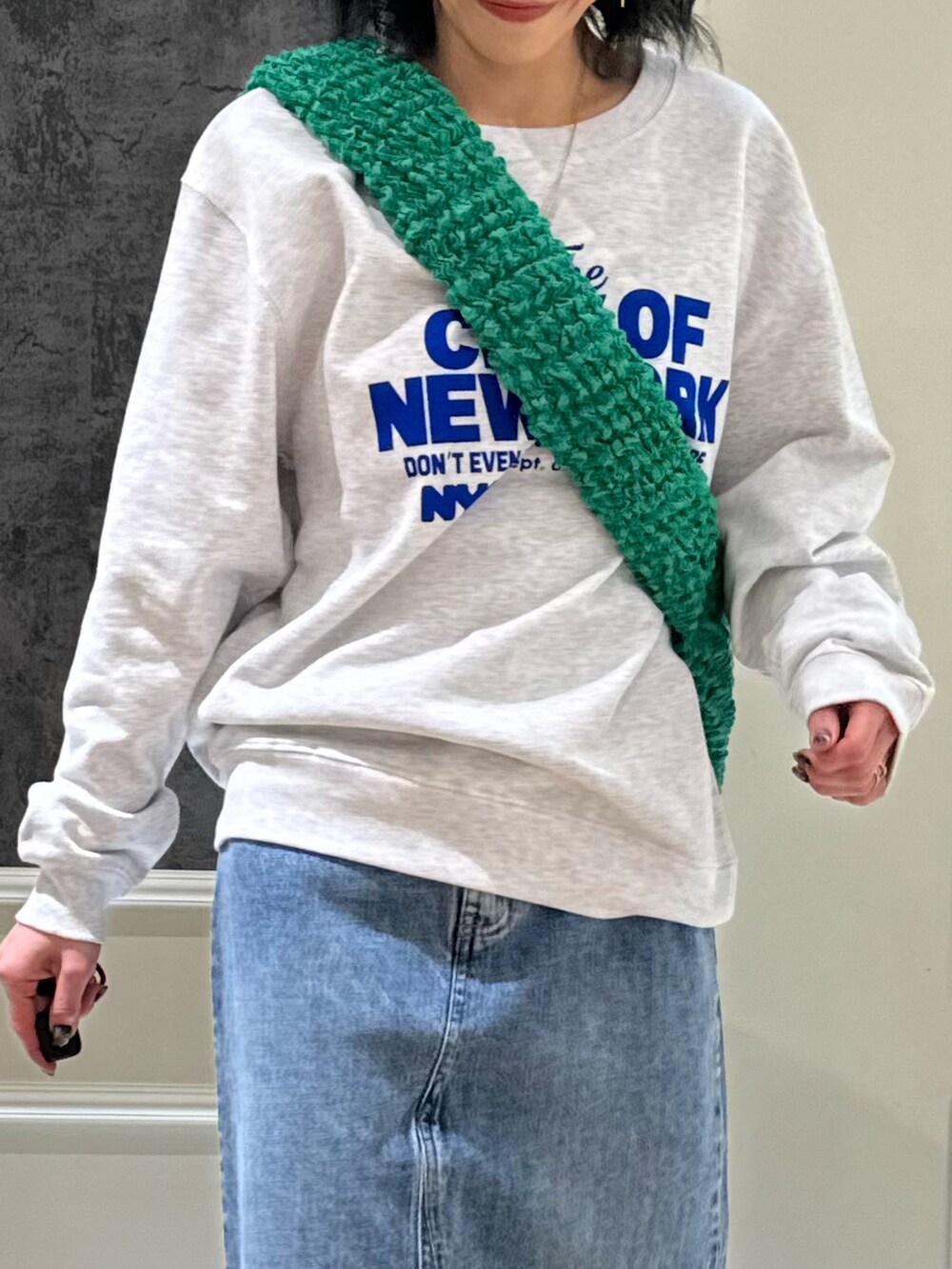 グレー系のスウェット、ブルー系のデニムスカート、ホワイト系のブーツを着用したレディースの冬コーディネートの3枚目の写真