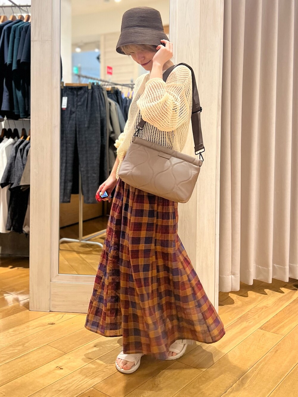 ホワイト系のニット/セーター、パープル系のスカート、シルバー系のクラッチバッグを着用したレディースの夏コーディネートの2枚目の写真