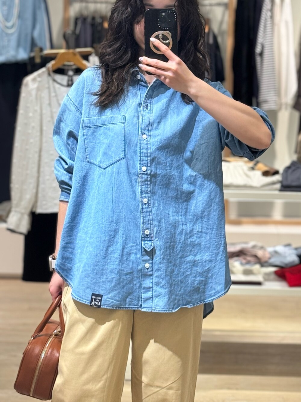 ブルー系のシャツ/ブラウス、ベージュ系のチノパンツ、イエロー系のショルダーバッグを着用したレディースの春コーディネートの2枚目の写真