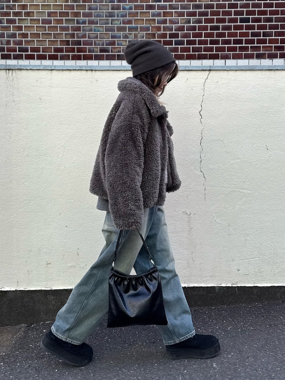 グレー系のムートンコート、ブルー系のデニムパンツ、グレー系のニット/セーターを着用したレディースの冬コーディネートの4枚目の写真