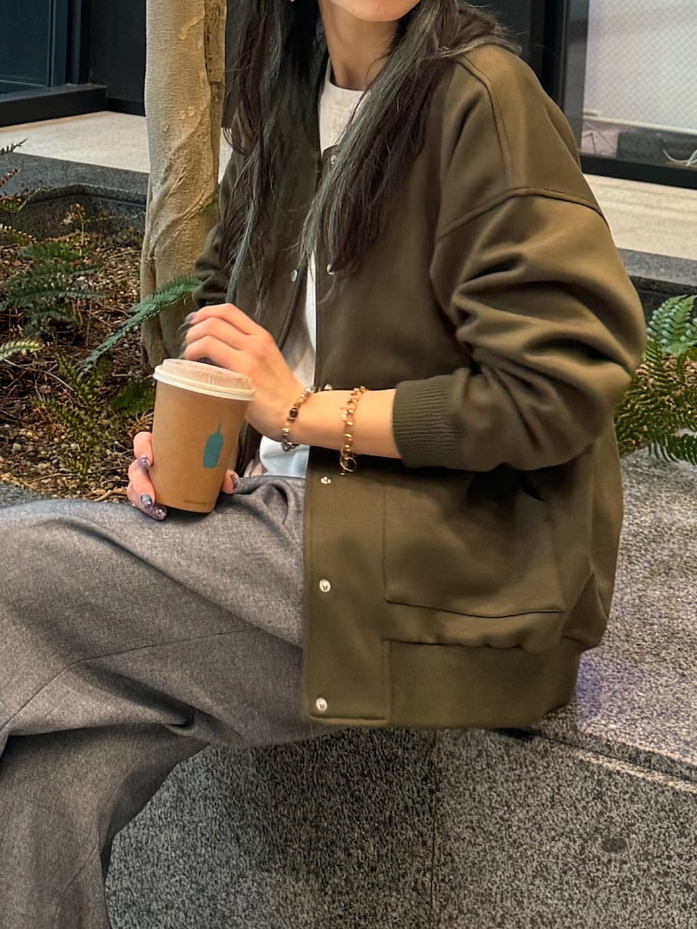 ブルー系のスラックス、グリーン系のブルゾン、ホワイト系のTシャツ/カットソーを着用したレディースの春コーディネートの2枚目の写真