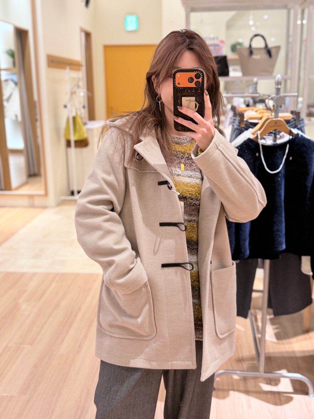 ベージュ系のダッフルコート、イエロー系のニット/セーター、グレー系のその他パンツを着用したレディースの冬コーディネートの2枚目の写真