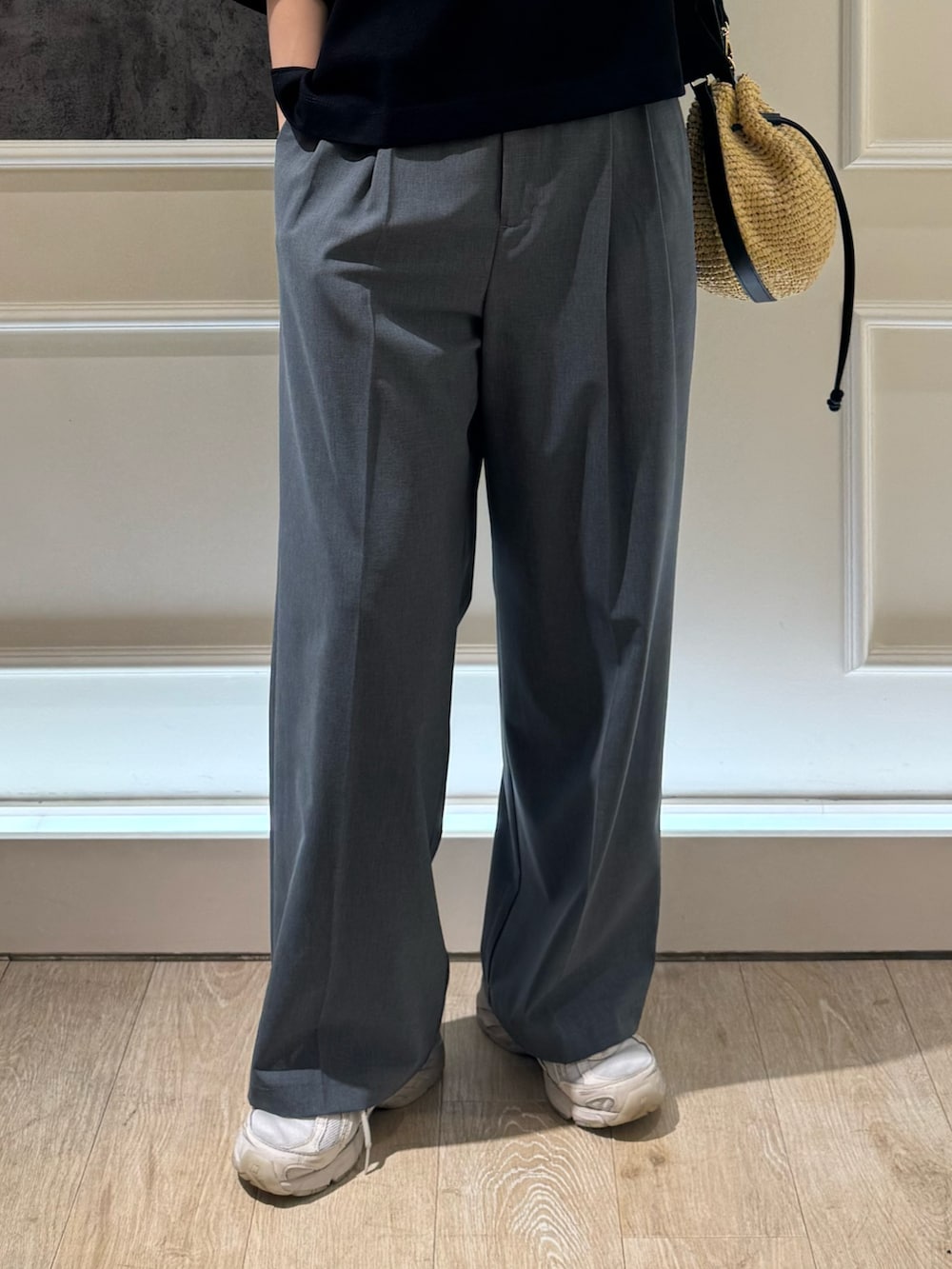 グレー系のTシャツ/カットソー、グレー系のスラックス、ベージュ系のかごバッグを着用したレディースの夏コーディネートの5枚目の写真