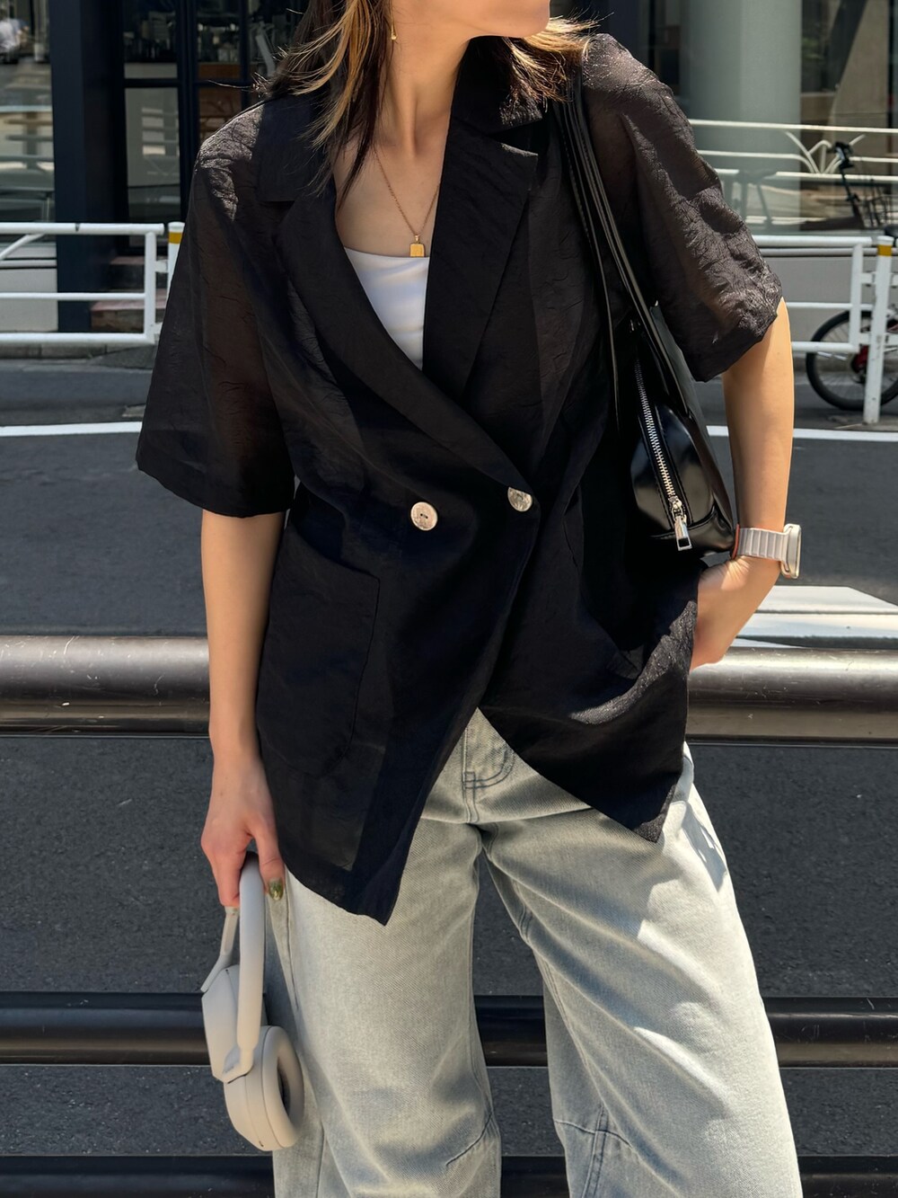 ブラック系のダウンジャケット/コート、ブルー系のデニムパンツ、ホワイト系のボストンバッグを着用したレディースの夏コーディネートの5枚目の写真