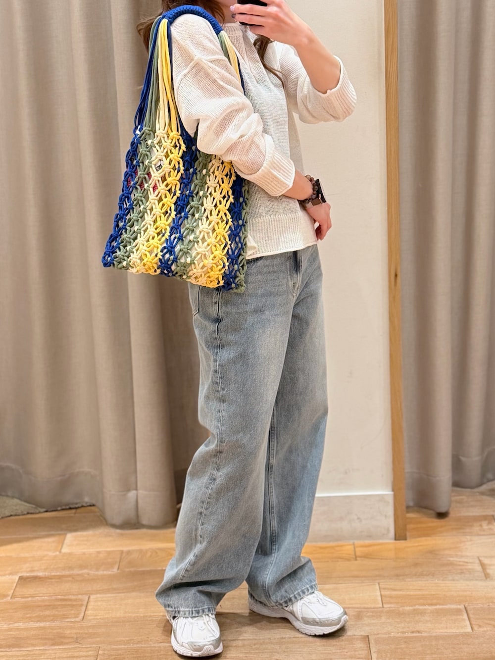 ホワイト系のニット/セーター、ブルー系のデニムパンツ、ブラック系のトートバッグを着用したレディースの春コーディネートの3枚目の写真