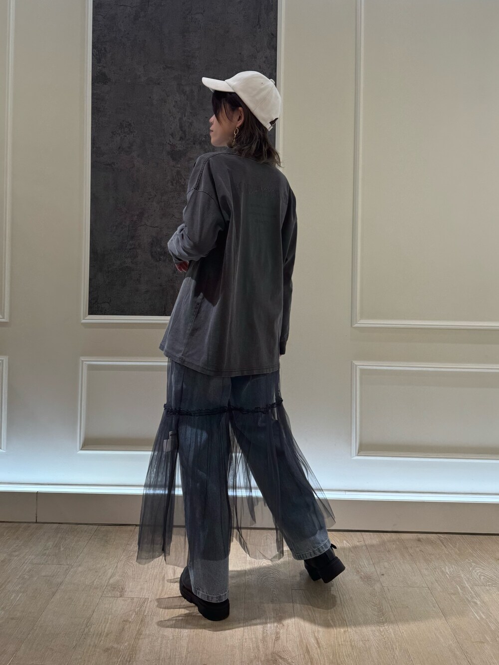 グレー系のTシャツ/カットソー、グレー系のスカート、ブルー系のデニムパンツを着用したレディースの冬コーディネートの4枚目の写真