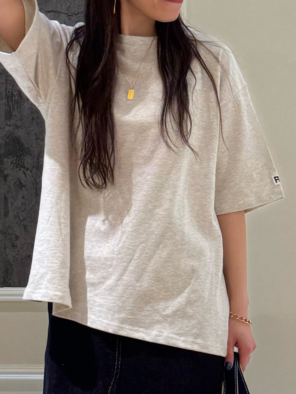 ベージュ系のTシャツ/カットソー、ブルー系のデニムスカート、ブラック系のトートバッグを着用したレディースの春コーディネートの5枚目の写真