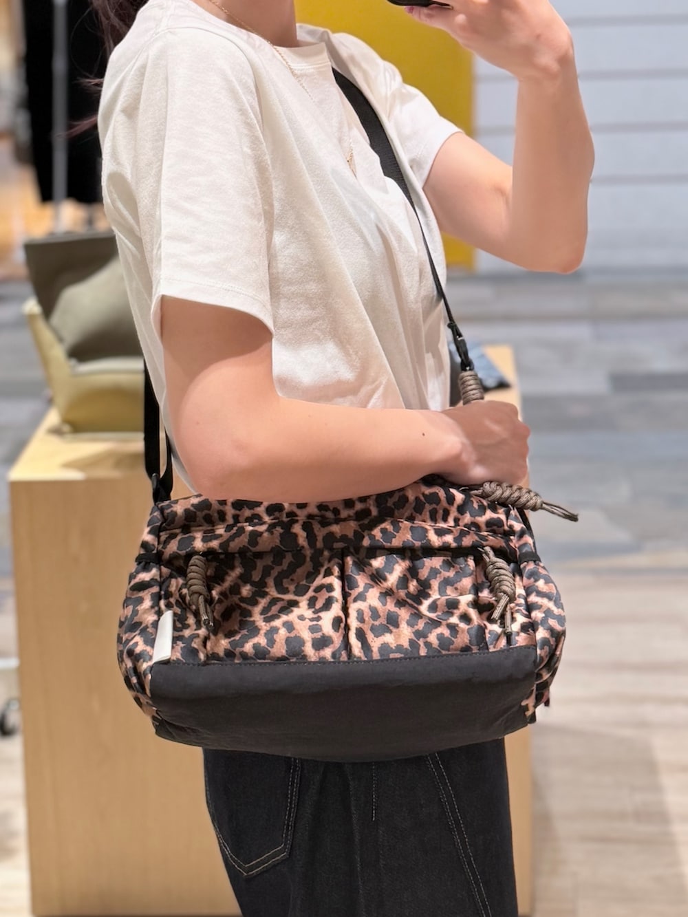 ブラウン系のショルダーバッグ、ホワイト系のTシャツ/カットソー、ブルー系のデニムパンツを着用したレディースの夏コーディネートの2枚目の写真