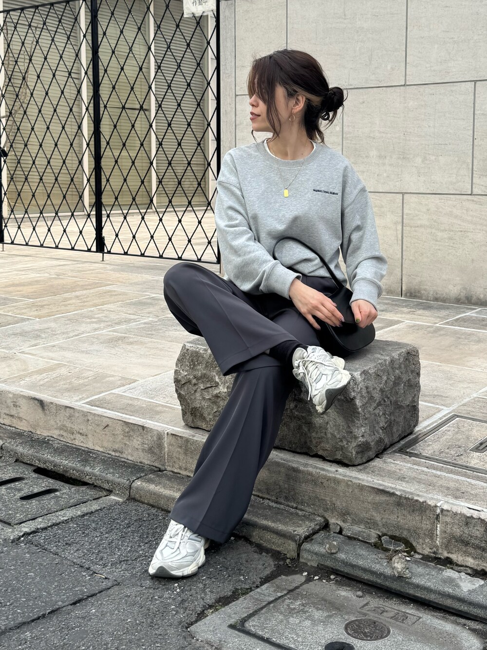 グレー系のスウェット、グレー系のスラックス、ブラック系のショルダーバッグを着用したレディースの春コーディネートの5枚目の写真