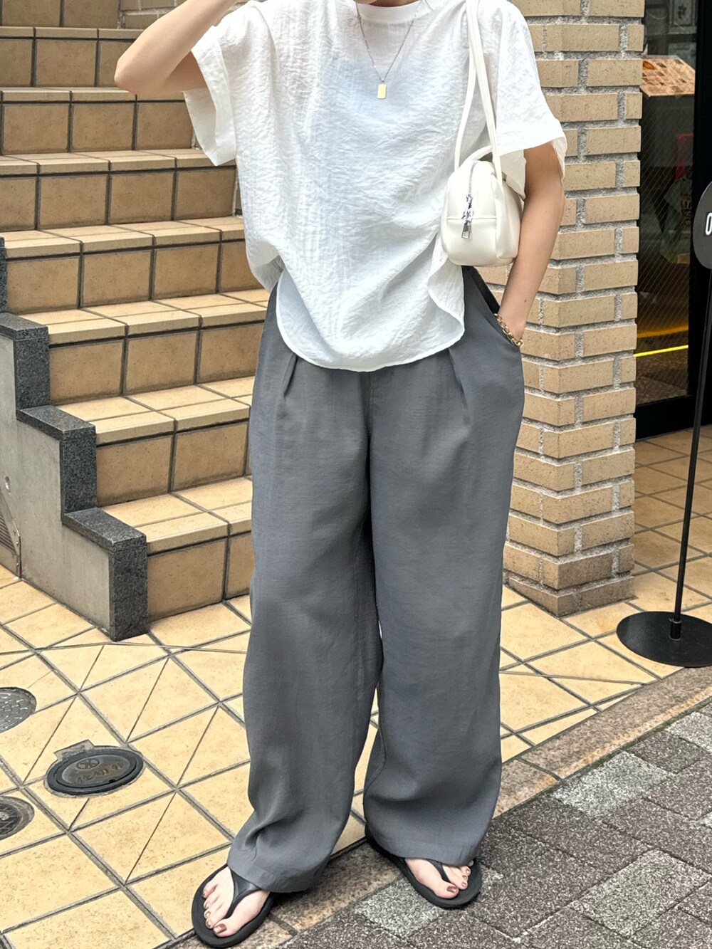ホワイト系のシャツ/ブラウス、グレー系のサンダル、グレー系のスラックスを着用したレディースの夏コーディネートの6枚目の写真