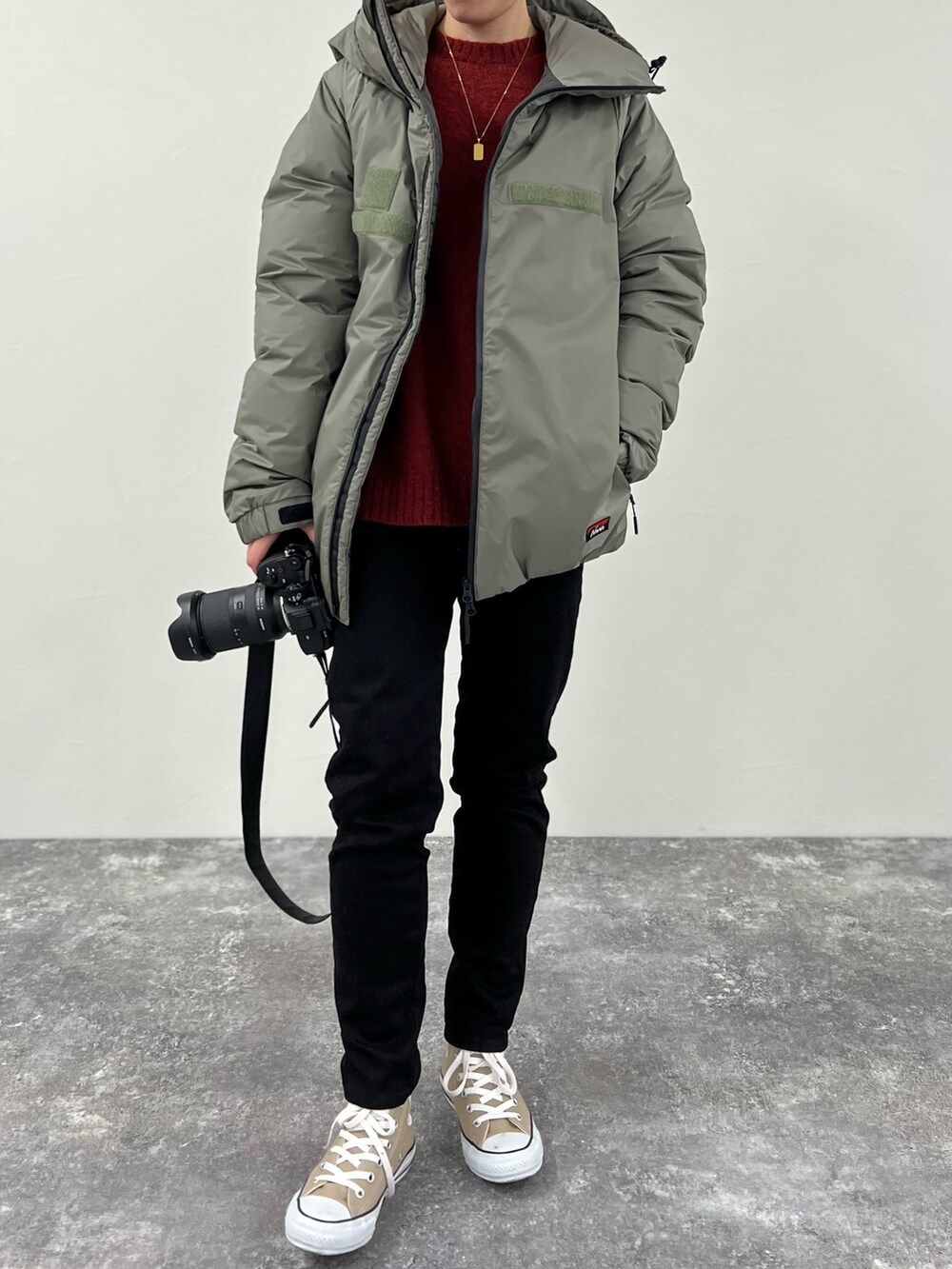 グリーン系のダウンジャケット/コート、ブラック系のデニムパンツ、レッド系のニット/セーターを着用したレディースの冬コーディネートの2枚目の写真