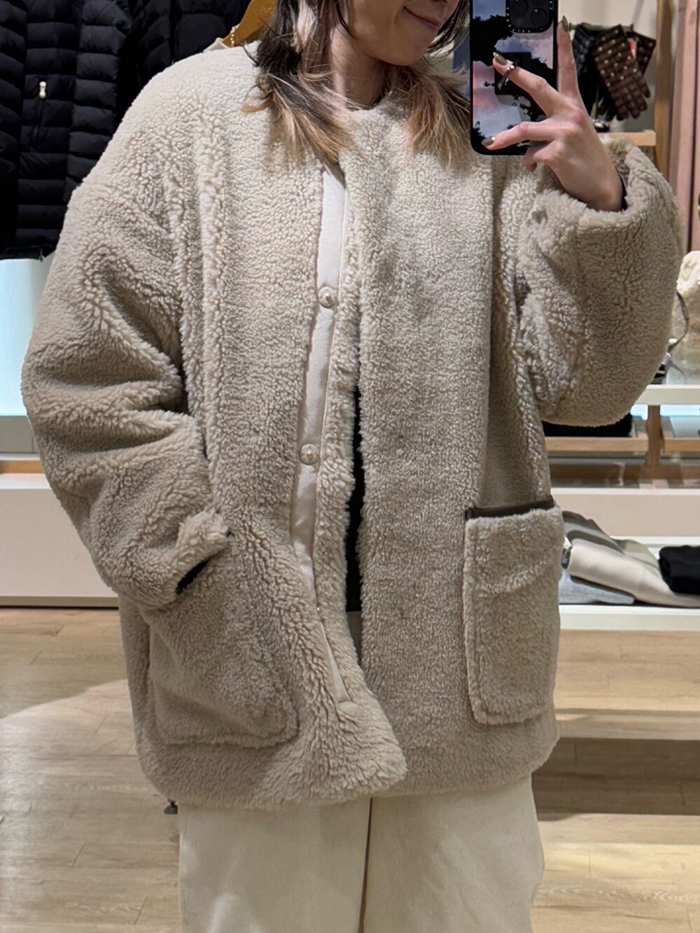 ブラウン系のノーカラーコート、ホワイト系のその他パンツ、グリーン系のニットキャップ/ビーニーを着用したレディースの冬コーディネートの2枚目の写真