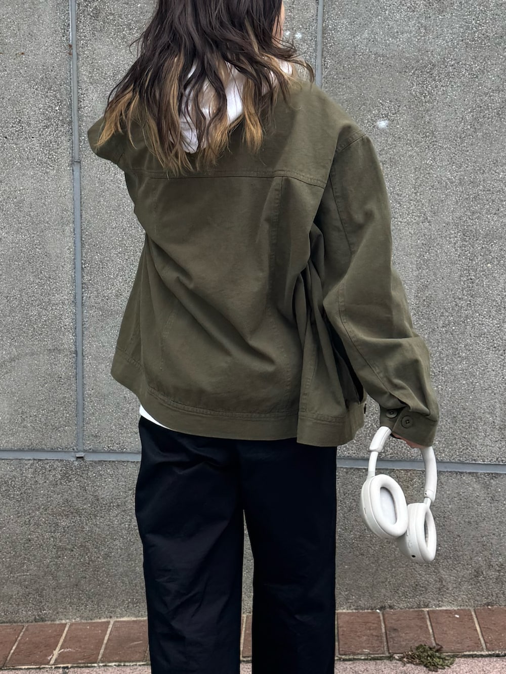 グリーン系のブルゾン、ホワイト系のパーカー、ベージュ系のチノパンツを着用したレディースの春コーディネートの3枚目の写真