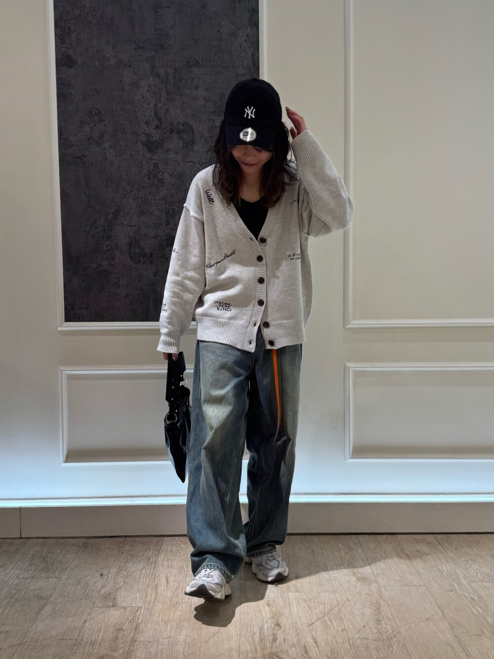 ホワイト系のカーディガン/ボレロ、ブルー系のデニムパンツ、ブラック系のショルダーバッグを着用したレディースの冬コーディネートの4枚目の写真